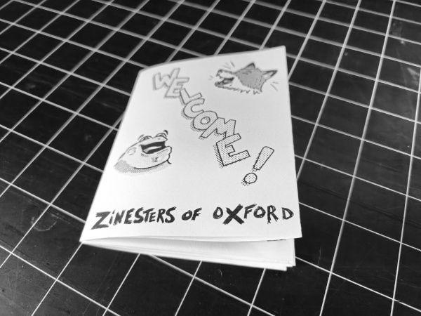 photo of a zine with a happy cartoon fox and frog on either side of the word WELCOME